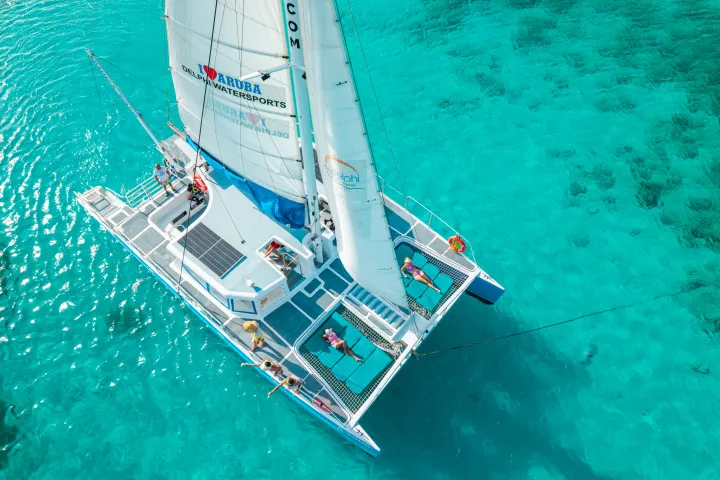 Aerial view of a catamaran with people on turquoise water.