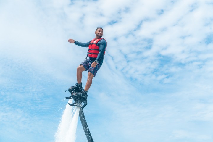 Person flyboarding over water with a cloudy sky background.