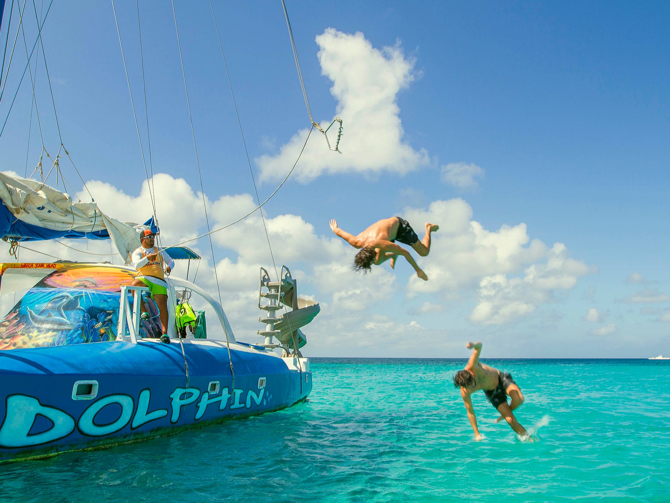 Men Jumping into the Ocean From the Dolphin