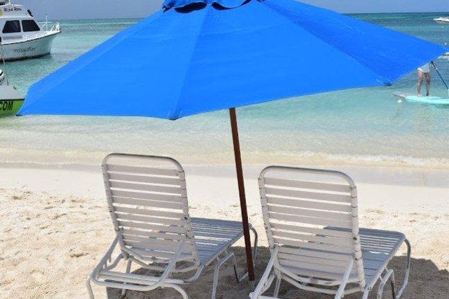a couple of lawn chairs sitting on top of a sandy beach