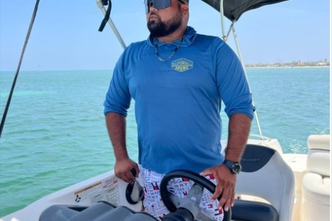 a man holding a fish on a boat in the water